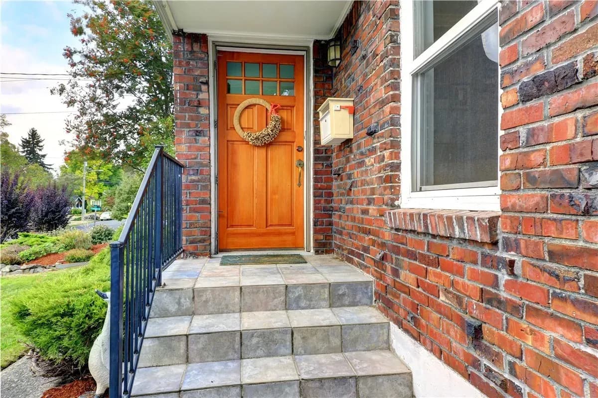 Brown entry door with wreath on brick home